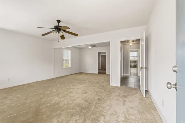 an empty room with ceiling fan and windows
