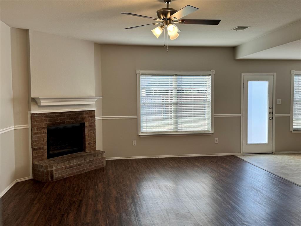 204 South Chestnut Street Forney, TX 75126 - Photo 3 of 19 an empty room with wooden floor a ceiling fan a fireplace and windows
