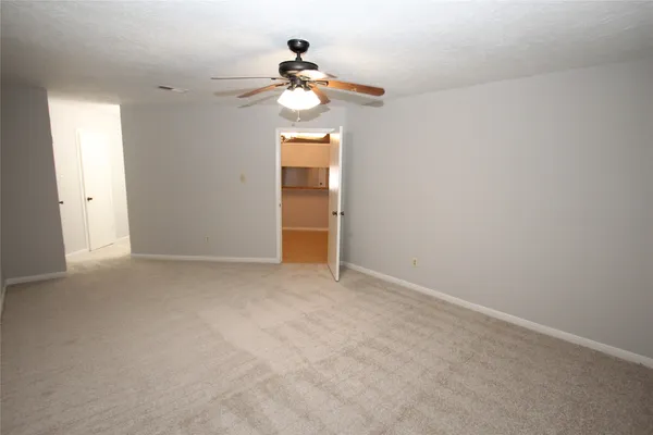 an empty room with a chandelier fan and windows
