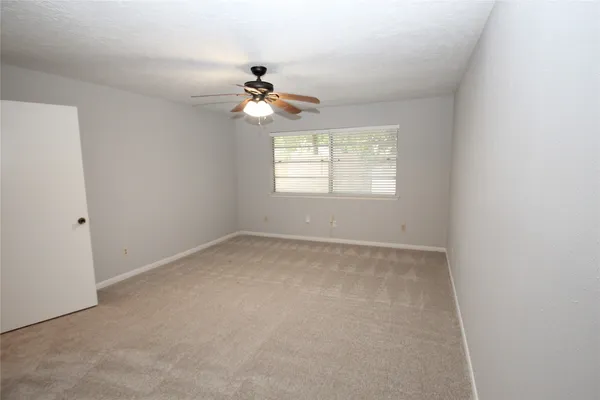 an empty room with windows and fan