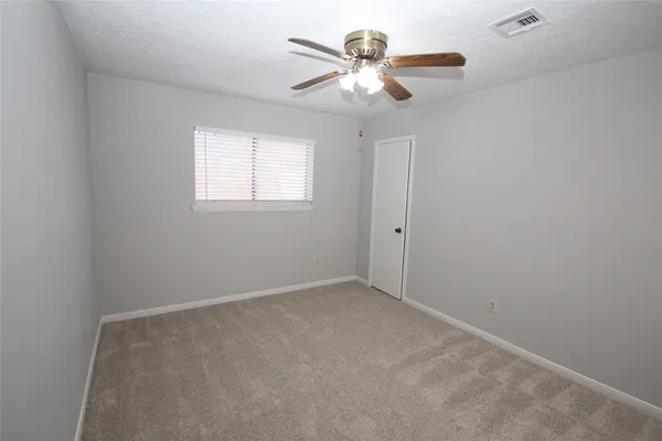 an empty room with a chandelier fan and windows