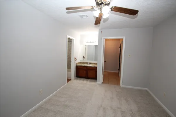 an empty room with a chandelier fan and a bathroom