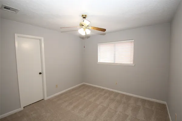 an empty room with a window and a fan