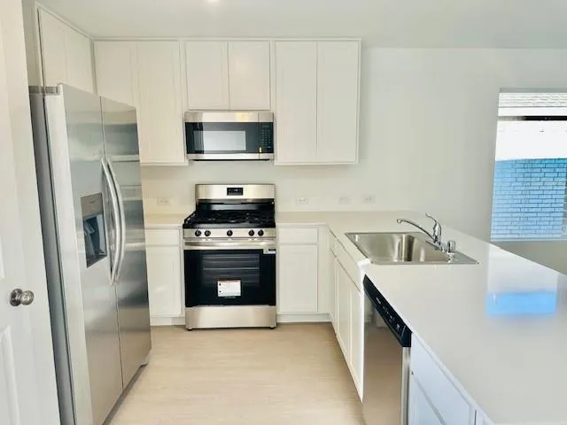 a kitchen with stainless steel appliances a stove a sink and a refrigerator