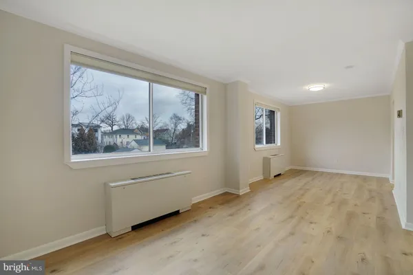a view of an empty room with a window and wooden floor
