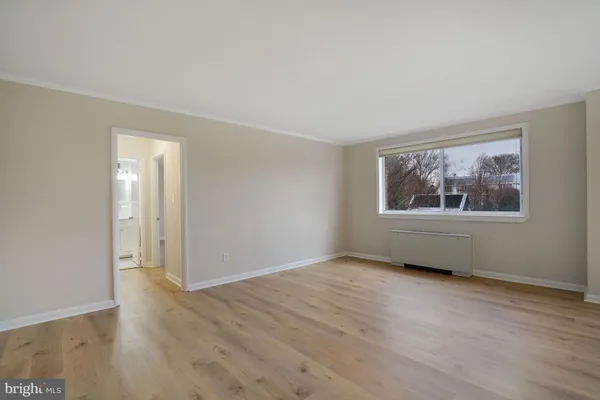 a view of an empty room with wooden floor and a window
