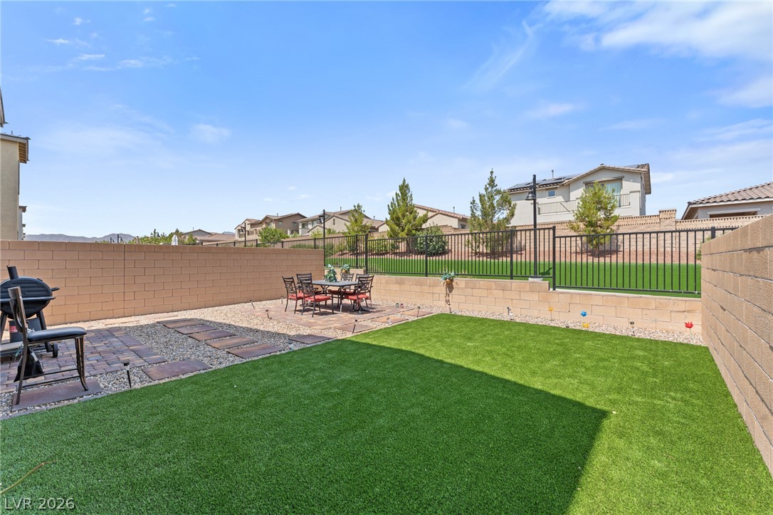 8879 Roadrunner Ravine Street Las Vegas, NV 89166 - Photo 34 of 39 A well-maintained outdoor space features a patterned patio, a lush green lawn, and secure fencing.