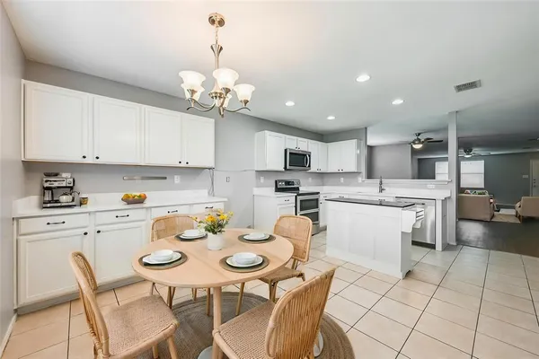 a white kitchen with a dining table chairs and white cabinets