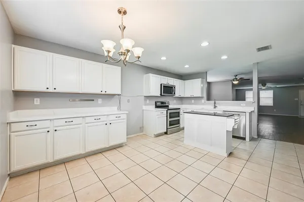 a kitchen with a white cabinets and chandelier