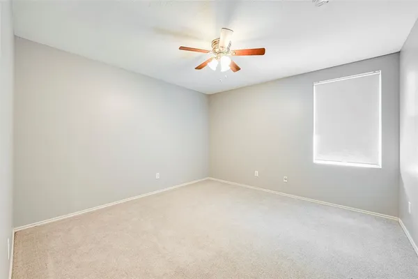 an empty room with windows and ceiling fan