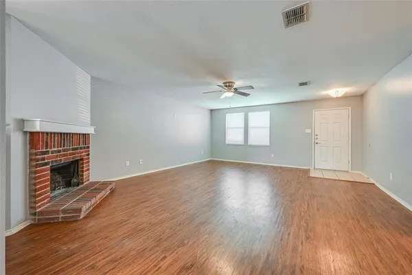 an empty room with wooden floor fireplace and windows