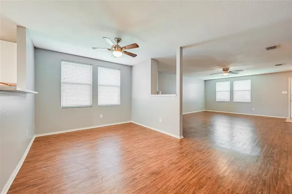 a view of an empty room with a window and wooden floor