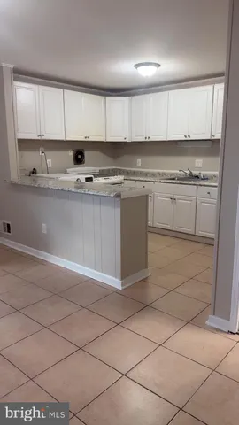 a kitchen with granite countertop a stove a sink and a white cabinets