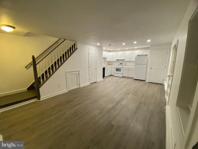 a view of an empty room with wooden floor and stairs