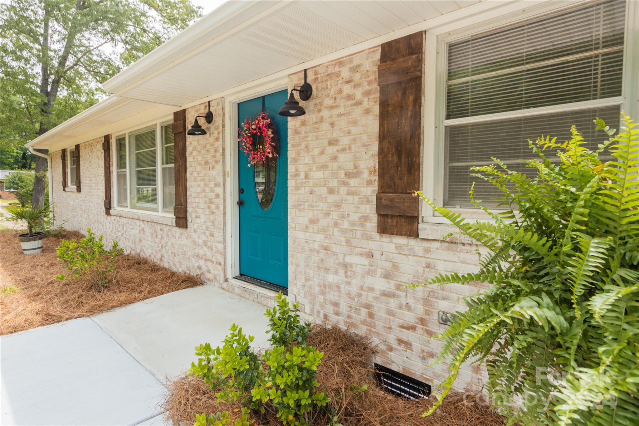 a front view of a house with a yard and potted plants