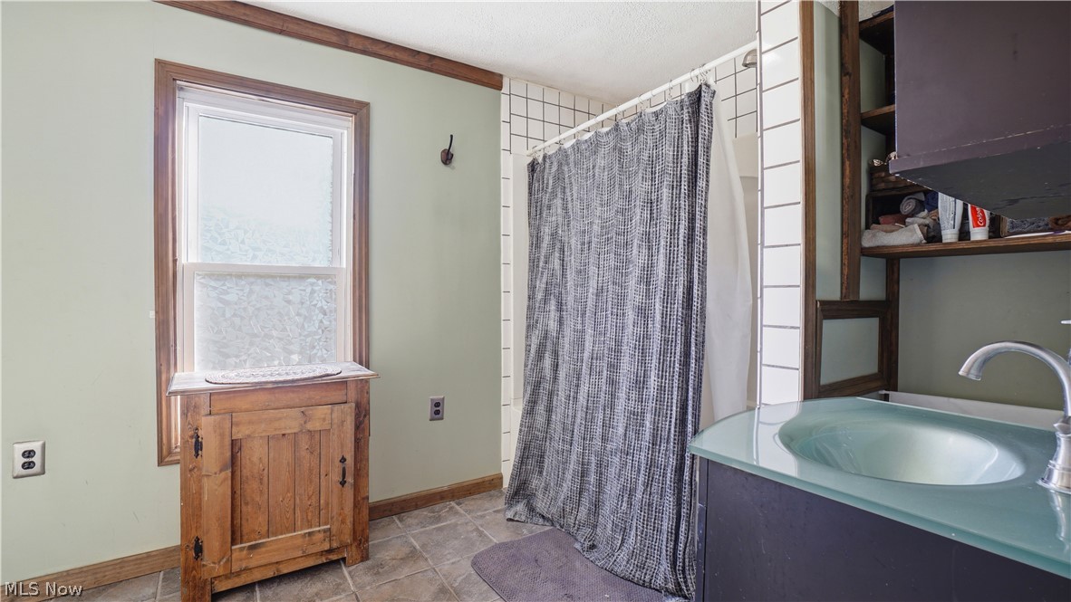 65892 Endley Road Cambridge, OH 43725 - Photo 34 of 50 Bathroom with vanity, light tile patterned flooring, and shower / bath combo with shower curtain