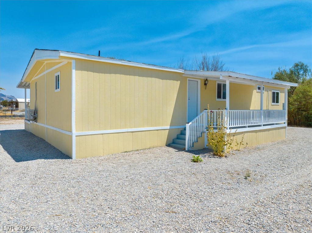 4081 Retread Road Pahrump, NV 89048 - Photo 59 of 98 A cheerful residence featuring a inviting covered porch and a spacious gravel lot.