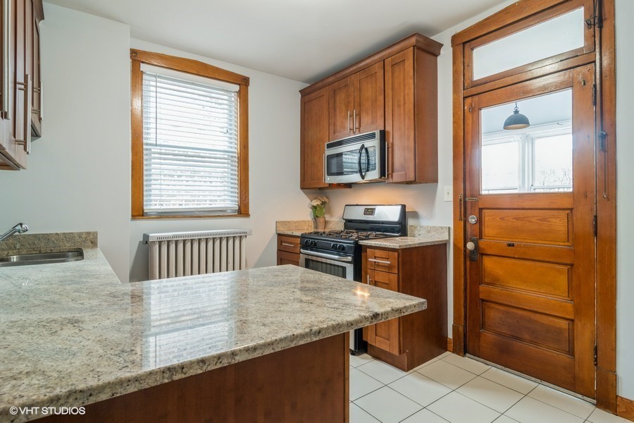 3935 North Christiana Avenue, Unit 2 Chicago, IL 60618 - Photo 7 of 12 a kitchen with stainless steel appliances granite countertop a stove a sink and a microwave