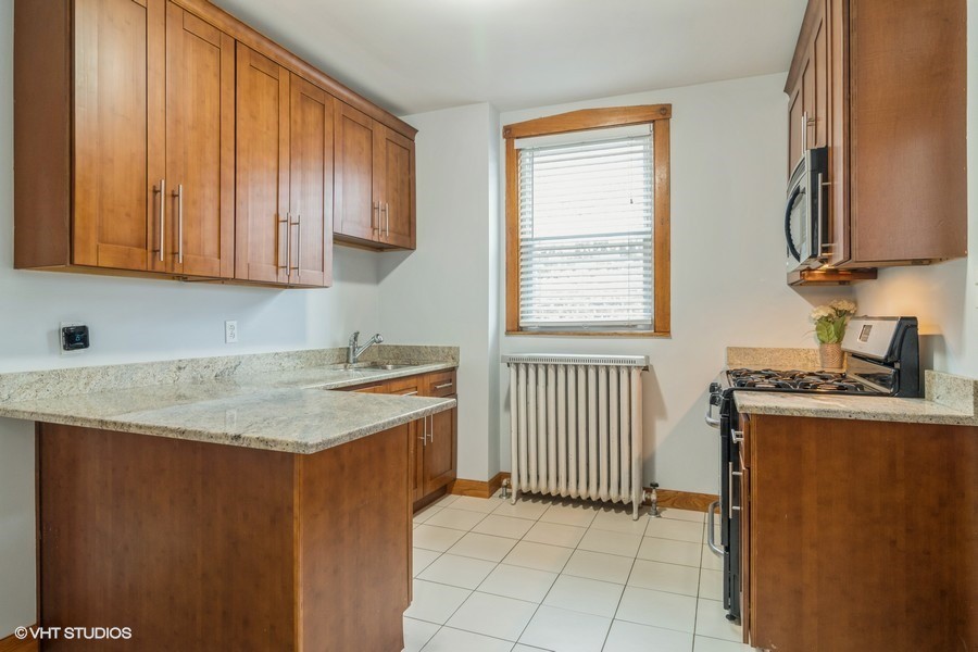 3935 North Christiana Avenue, Unit 2 Chicago, IL 60618 - Photo 8 of 12 a kitchen with granite countertop cabinets stainless steel appliances a sink and a window
