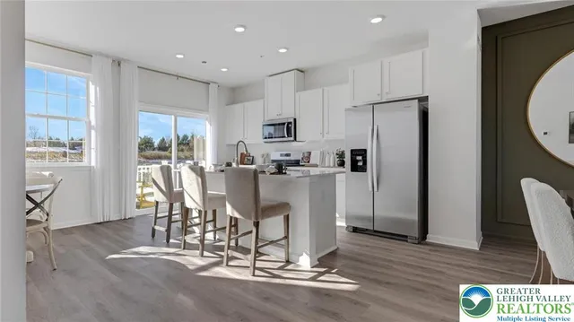 a kitchen with stainless steel appliances granite countertop a refrigerator a stove top oven and a dining table with wooden floor