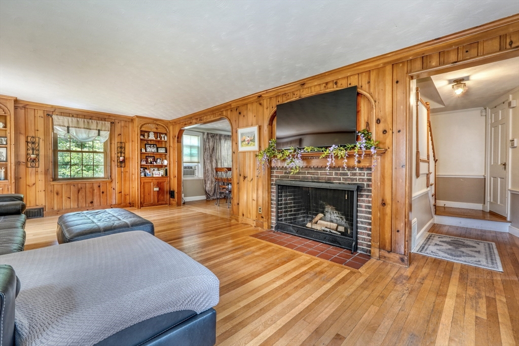 27 Ledyard Road Winchester, MA 01890 - Photo 3 of 38 a living room with a couch a fireplace a flat screen tv and floor to ceiling window
