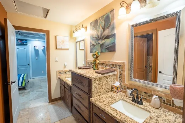 a bathroom with a granite countertop sink a mirror and a shower