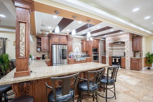 a kitchen with stainless steel appliances granite countertop a table chairs and a refrigerator