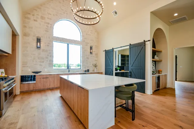 a kitchen with stainless steel appliances granite countertop a stove a refrigerator a kitchen island a dining table and chairs with wooden floor