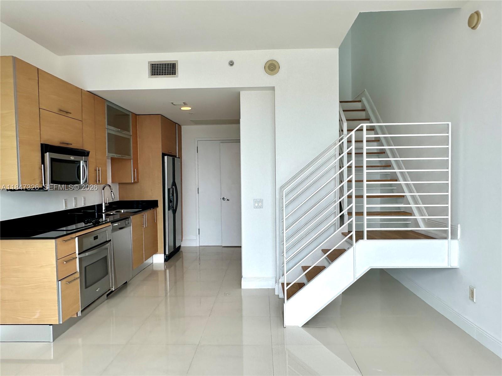 60 Southwest 13th Street, Unit 1605 Miami, FL 33130 - Photo 3 of 25 a view of a kitchen with a sink and dishwasher a stove top oven with wooden floor