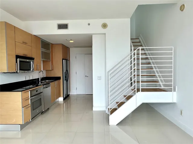 a view of a kitchen with a sink and dishwasher a stove top oven with wooden floor