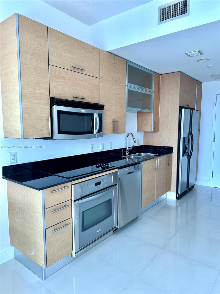 60 Southwest 13th Street, Unit 1605 Miami, FL 33130 - Photo 7 of 28 a kitchen with granite countertop white cabinets and stainless steel appliances