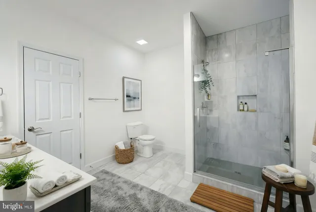 a bathroom with a granite countertop sink a toilet and shower
