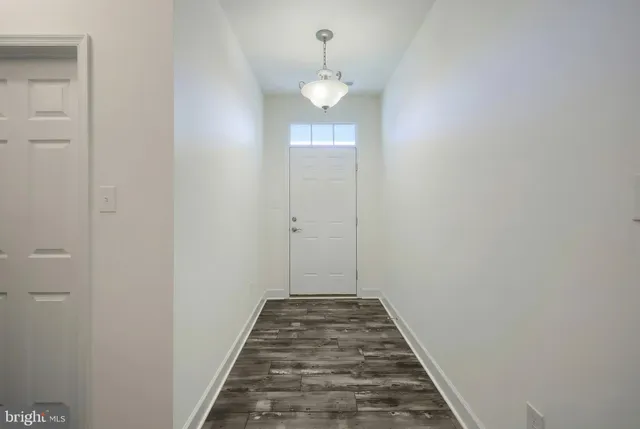 a view of a hallway with wooden floor and a chandelier