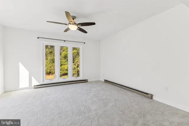 an empty room with ceiling fan and window