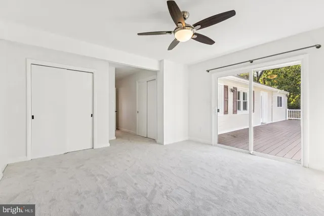 an empty room with ceiling fan and window