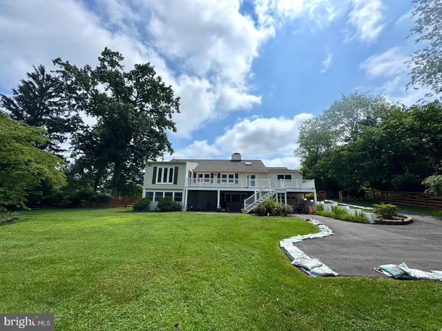 a view of a house with a big yard and potted plants and large trees
