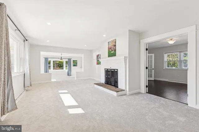 an empty room with windows and fireplace