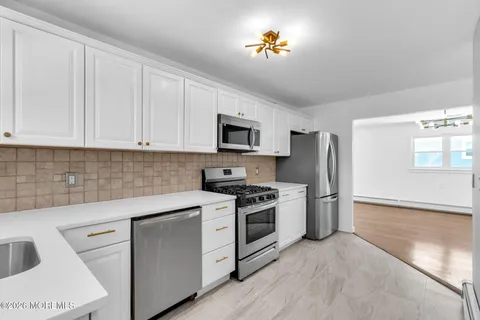 a kitchen with stainless steel appliances granite countertop a stove a sink dishwasher and a refrigerator with wooden floor