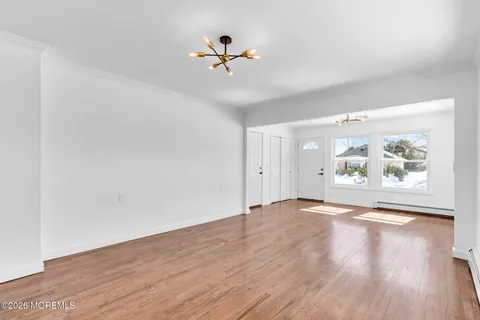 an empty room with wooden floor chandelier fan and windows