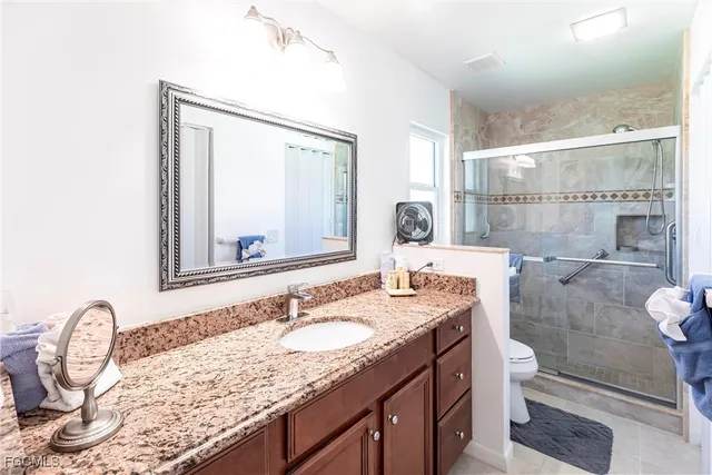 a bathroom with a granite countertop sink a toilet and a mirror