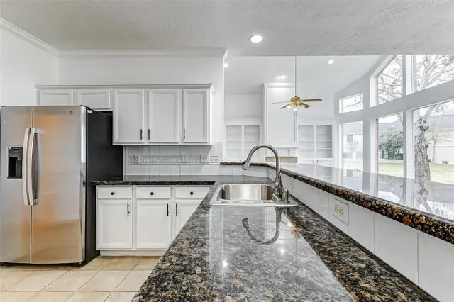 a kitchen with granite countertop a large window and a refrigerator