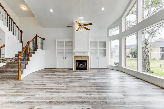a view of a livingroom with a fireplace ceiling fan and windows