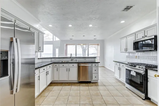 a large kitchen with stainless steel appliances granite countertop a stove and a sink
