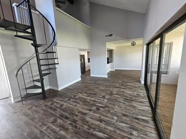 a view of an empty room with wooden floor and stairs