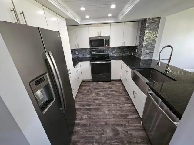 a kitchen with granite countertop a refrigerator and a sink