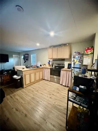 a large kitchen with stainless steel appliances granite countertop a stove top oven a sink dishwasher and cabinets with wooden floor