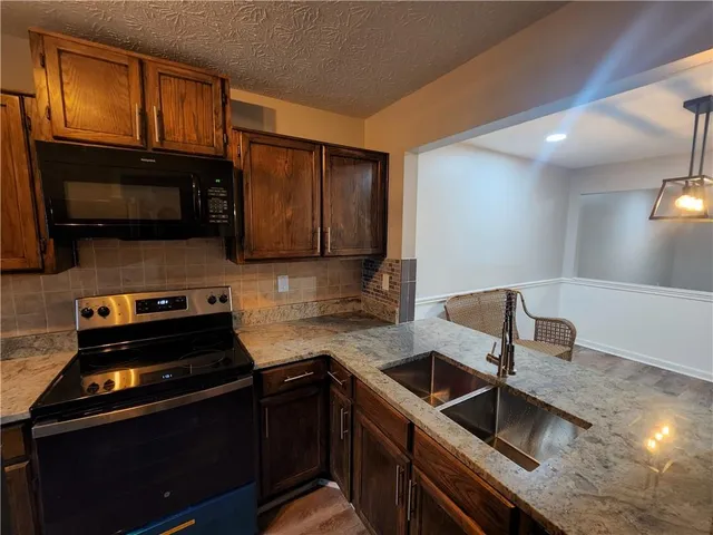 a kitchen with granite countertop a sink stove and microwave