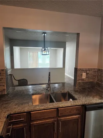 a kitchen with kitchen island granite countertop a sink a stove and a microwave oven