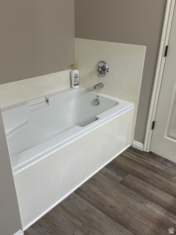 14797 South Chandlerpoint Way Draper, UT 84020 - Photo 18 of 33 White bathtub with chrome fixtures, a cream-colored tile surround, and wood-finish flooring