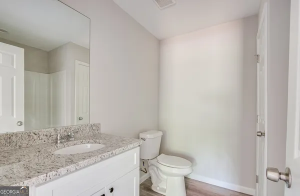 a bathroom with a granite countertop sink a toilet and a mirror